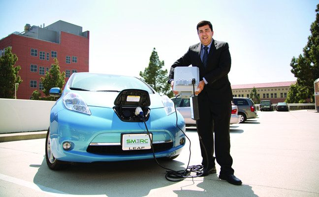 UCLA professor Rajit Gadh holding prototype battery plugged into car