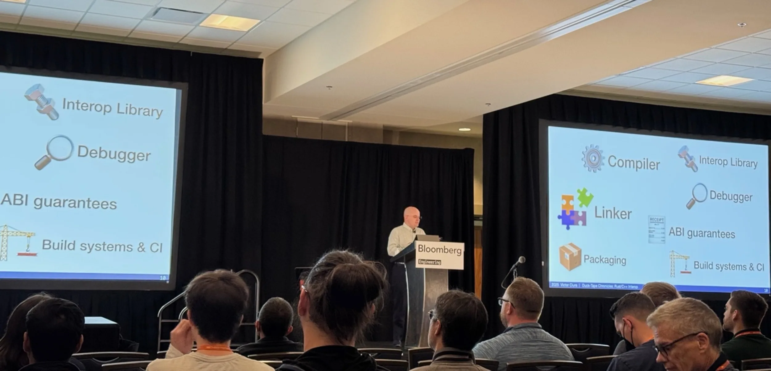 A man standing in between two projector screens showing content for a talk on Rust and C++ interoperability