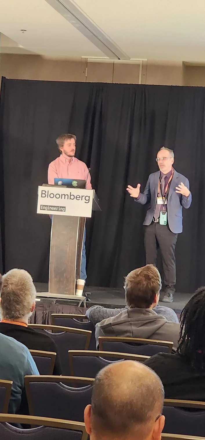 Image of two people standing at a lectern giving a CppCon talk
