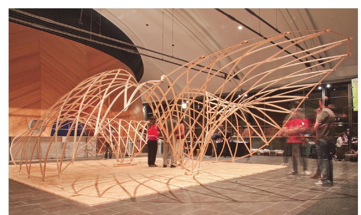 Figure 5: The Smart Geometry Gridshell was a proof-of-concept of this approach resulting in a formal type that could not have been constructed through the flat matt technique.  Along with streamlining the previous work of the Parametric Wood Sem- inar, form-finding was integrated into this workflow through the introduction of Kangaroo.This solution established the boundary condition from a catena- ry control rig, from which the surface was form-found through a network of springs in Kangaroo which balanced the equalization of spring lengths (sur- face relaxation) with an upwards load vector (inverse hanging-chain mod- el).Curvature analysis was employed to make sure that the individual 1 2” x Ys” pine laths could be bent into the shape proposed (Figure 6). 