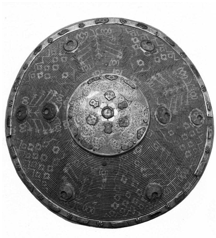 Fig. 7. Kalkan shield, Armenian workmanship, lat- ter half 17 century (The Royal Castle of Wawel)  Lwow they were especially known as the makers or decorators of various weaponry parts. They made “embroidery on yuft leather, chamois, quiver and bow cases, saddle bags, sad- dles, [...] saddle blankets and other things needed by soldiers”.** Armenian goldsmiths prided themselves for making “costly sabre settings, rich decoration of horse tack, detailed smithing of shields, kalkan shields, chain mail hoods, quivers and cartridge boxes in gold and silver.” Armenians made excellent, flexible and strong sabres which they often deco- rated with oriental hilts scabbards.° Parts and pre-fabricated elements were imported from the East, which was the speciality of, among others the trading house of the Nikorowicz family.” The elements were then put together and fitted. It is therefore not easy to dis- tinguish Armenian production from Oriental imports. Such is the case of several dozer kalkans preserved in Poland. The majority of these round shields are typical of Turkish art. A number of such objects in the Wawel collection seem to be the work of Armenian craftsmen, according to Zdzistaw Zygulski Jun.  Armenian artisans worked not just in Lwow. In ZamoS¢, in 1585, Murat Jakubowicz 