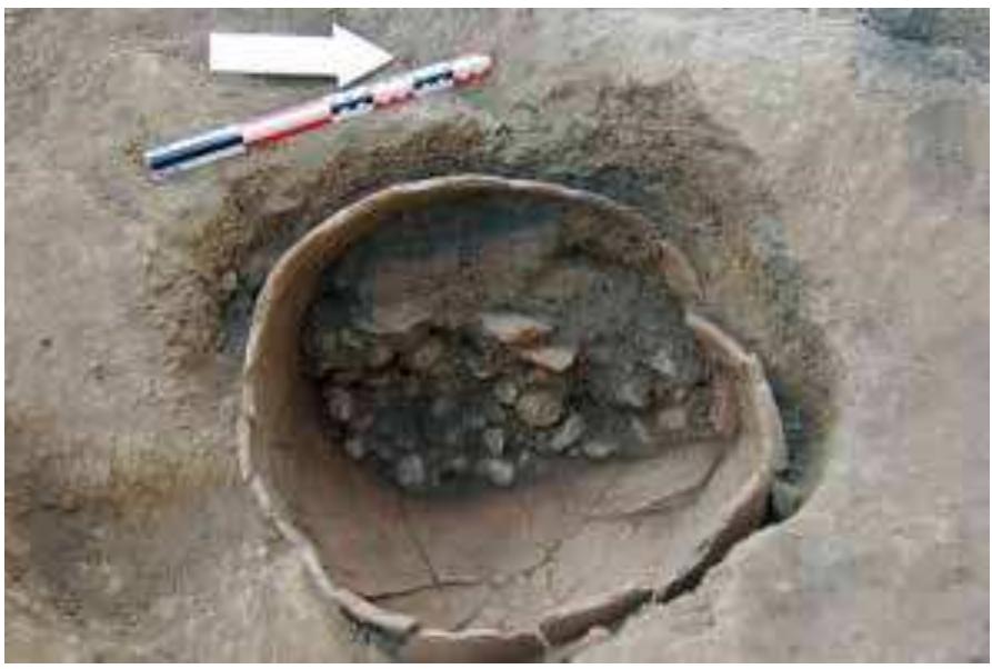 Fig. 24 The Early to Middle Bronze Age settlement layers  at Pheneos in the Korinthia revealed a pithos, which was  half-filled with pebbles (photo courtesy of the Institute of Archaeology, University of Graz)  Hi. iViivliadvld 4avVaAUIL  M. Zavadil continued studying the MH pottery from the acropolis excavations at Pheneos (Ko- rinthia/Peloponnese) in the museum at Pheneos, and in 2017 her work focused on the abundant MH III pottery. Macroscopic analysis suggests a change in the main (local or broadly local?) fabrics between the earlier Middle Bronze Age and MH II. While schist characterises the main fabric of the earlier pottery, mudstone temper seem to have been favoured in MH III. After the pertinent permission of the Greek Ministry of Culture had been received, Clare Burke took samples of 147 sherds for petrographic analysis in September 2017. The samples cover the  chronological span from EH III/MH I to LH II with emphasis on the early and late Middle Bronze Age. 