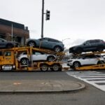 A truck wtih a car carrier trailer carries several new vehicles