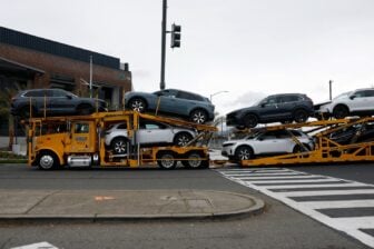 A truck wtih a car carrier trailer carries several new vehicles