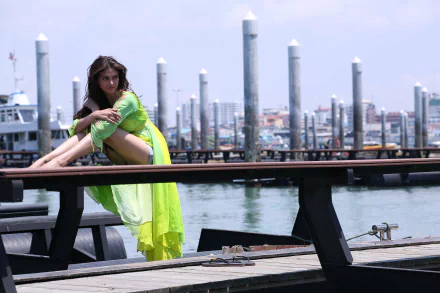Aditi Rao Hydari featured in a Bollywood-themed, HD desktop wallpaper. She poses on a dock in a vibrant green outfit, with a background of boats and cityscape under a clear sky.