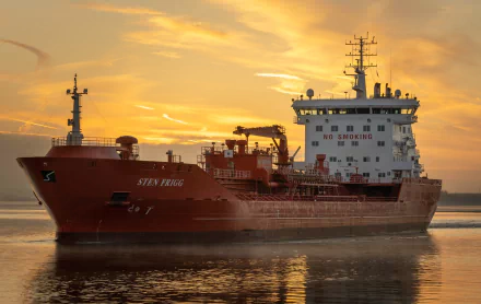 HD desktop wallpaper of a red tanker vessel named Sten Fjord on calm water during a golden sunset.