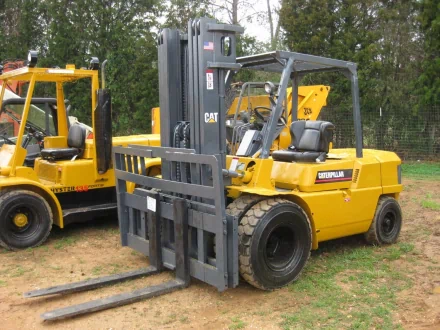 HD desktop wallpaper featuring a yellow Caterpillar Inc. forklift vehicle parked outdoors on grass with trees in the background.