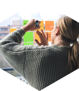 A woman jotting down notes to the sticky notes placed on a window.