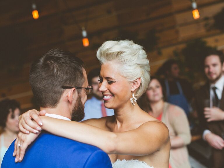 Bride smiles while dancing with her husband at their wedding reception. 