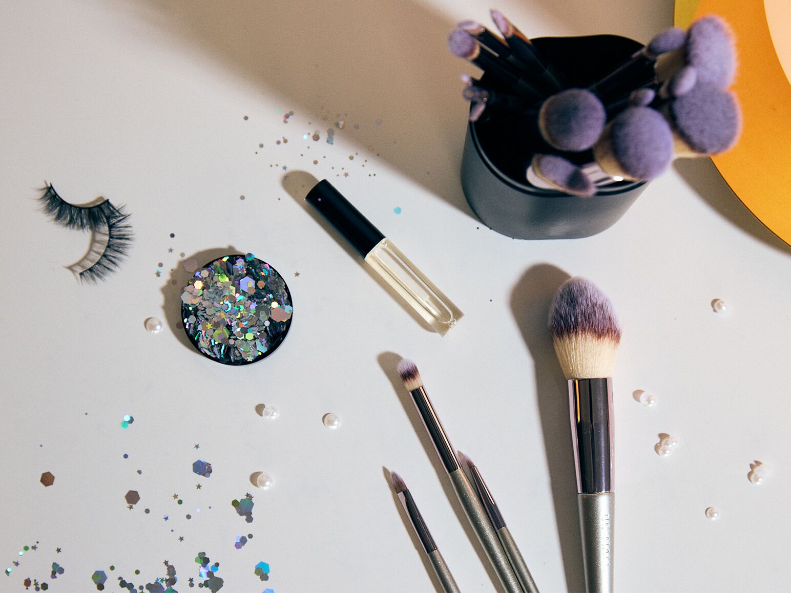 Table with makeup brushes, false lashes and sequins