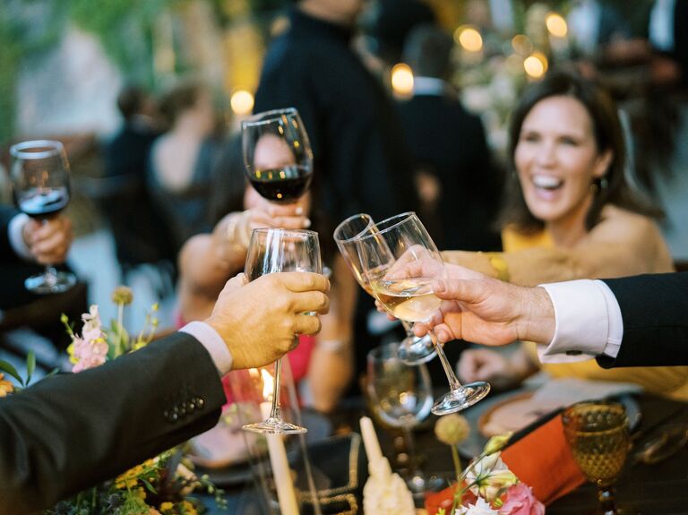 close-up of hands raising wine glasses for a toast