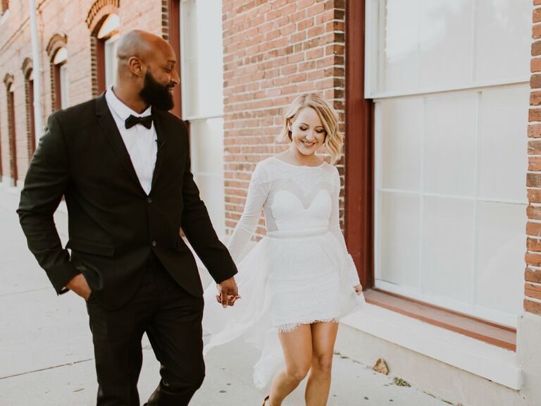 Bride wearing her hair in a modern lob walks hand in hand with her husband. 