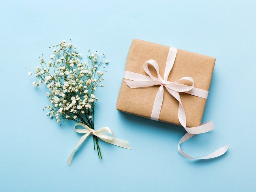 A wrapped wedding gift beside fresh florals