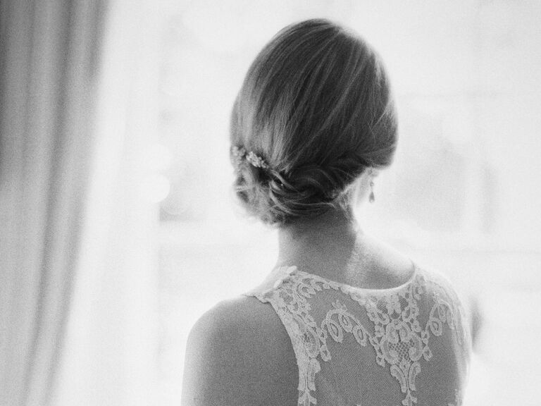 Bride looks away, showing off a sleek and timeless chignon. 