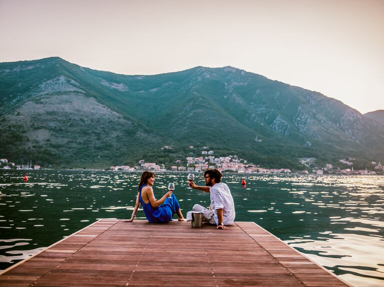 Couple toasting wine glasses on a lake