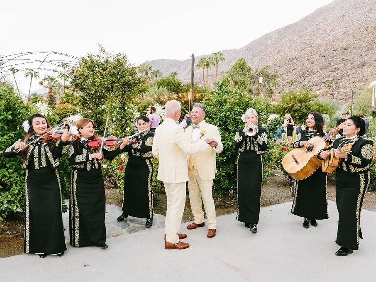 Grooms dancing in front of mariachi band at wedding reception