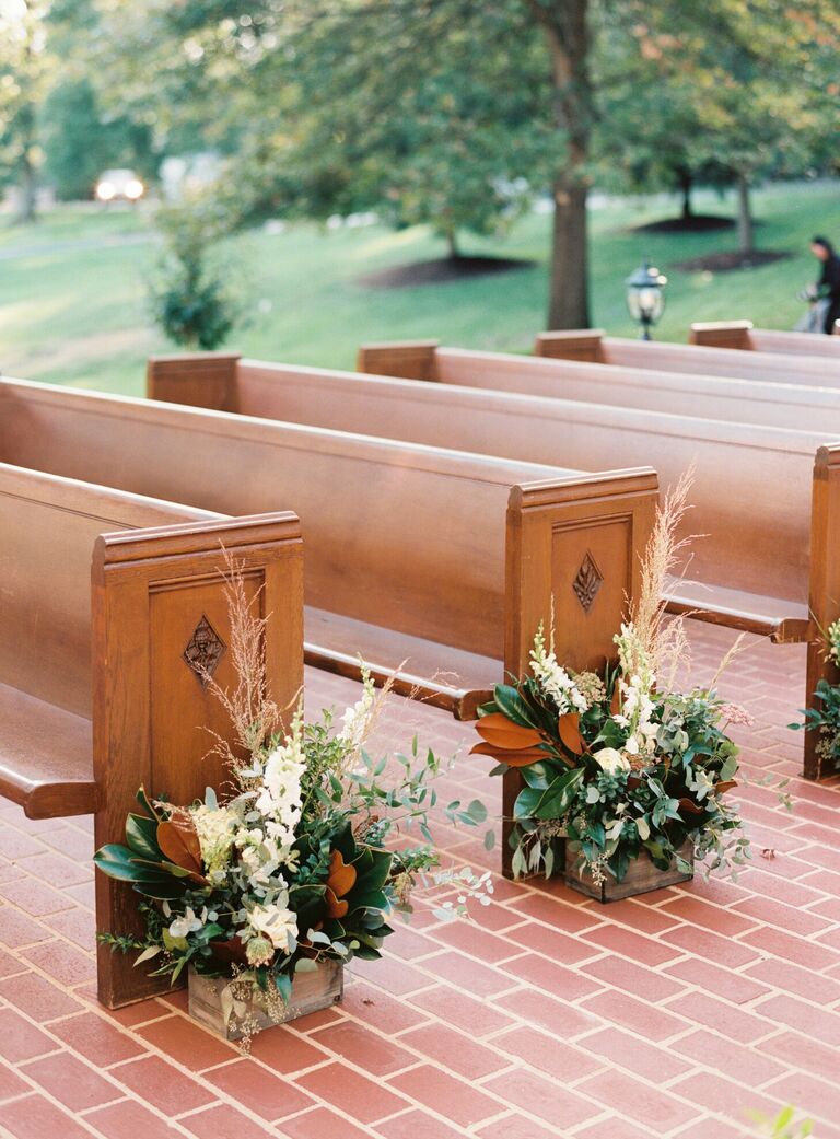 Wood pews accented by magnolia leaf arrangements