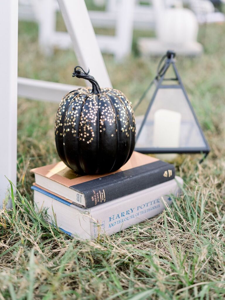 Black pumpkin decorated with gold stars at a Halloween wedding