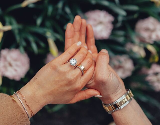 engagement announcement photo with couple holding hands and bride wearing round diamond engagement ring