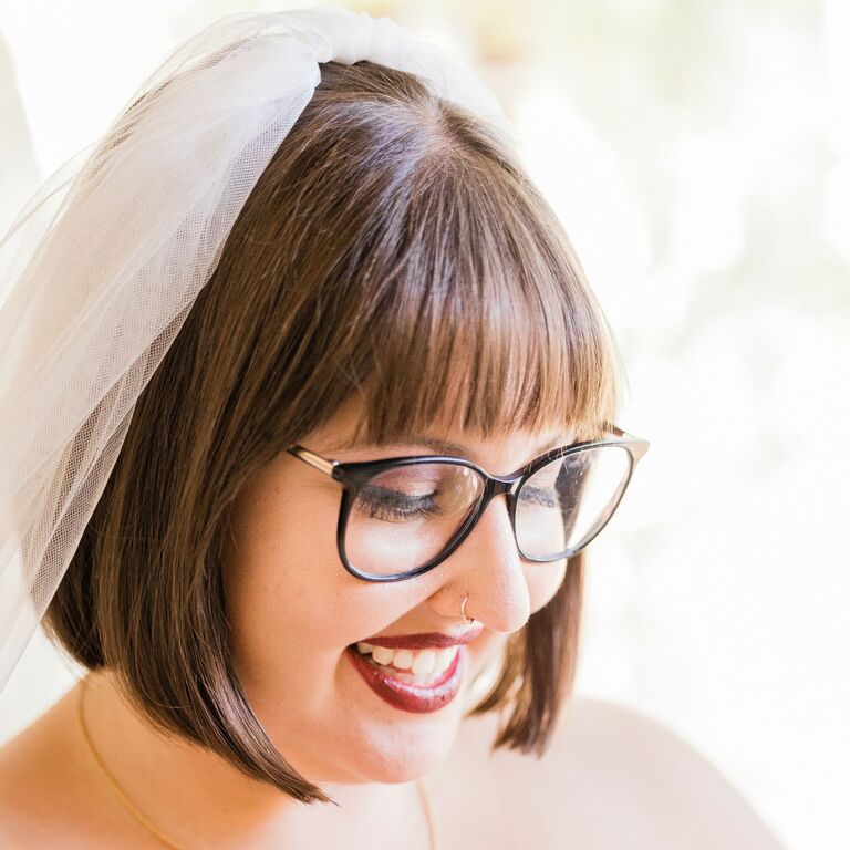 Bride wears her hair in a short bob with textured bangs and an elegant veil. 