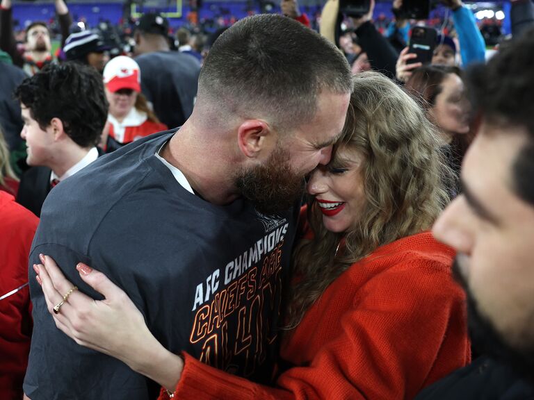 Travis Kelce and girlfriend Taylor Swift hugging on the field