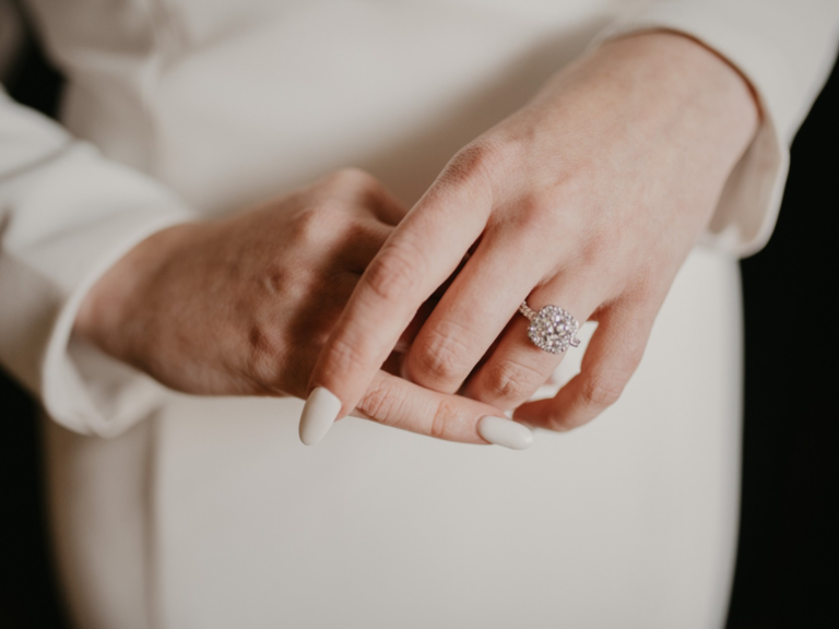 Woman's hands with cream wedding nail manicure and diamond ring