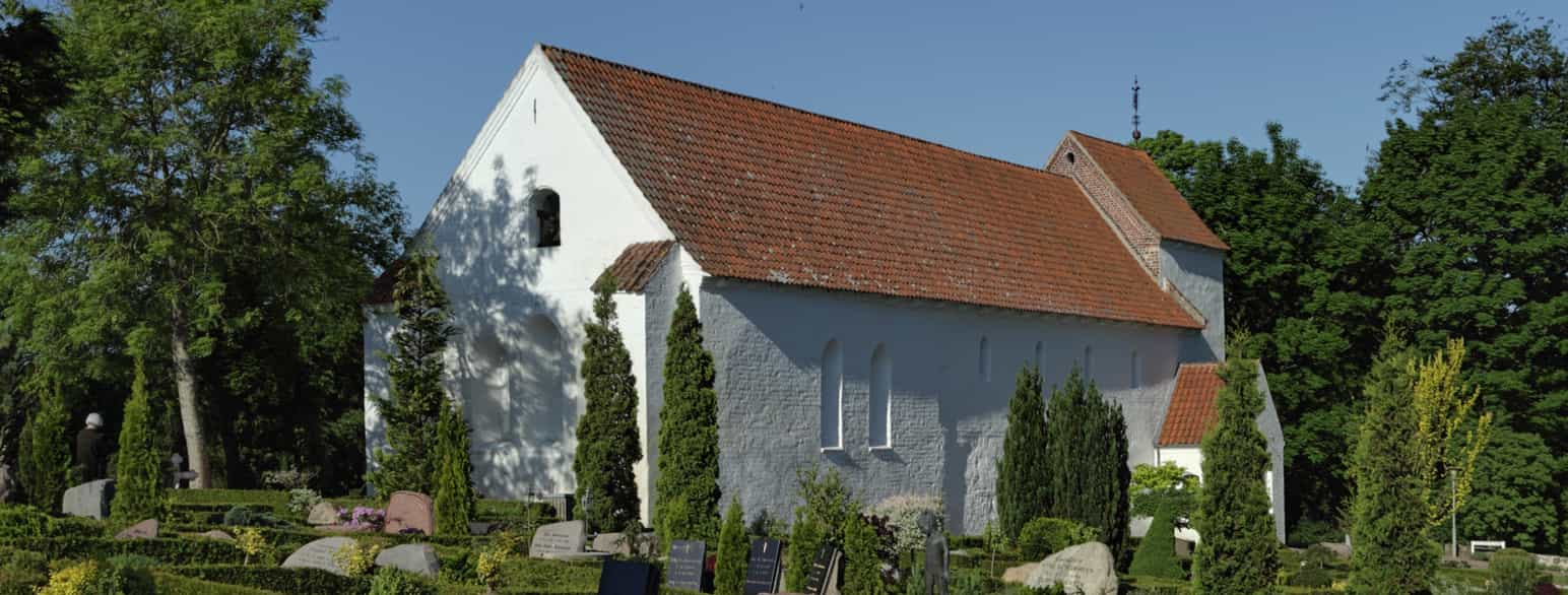 Asmild Kirke set udefra. Kirken består af et langhus og et lavt tårn i vest. Kirken er hvidkalket med rødt tegltag.