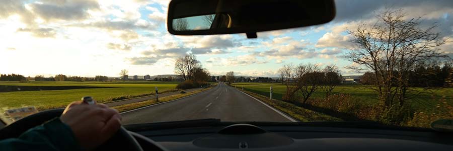 view through a car's windshield of the road and surrounding countryside