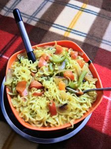 A bowl of indian style noodles with pepper and tomatoes.
