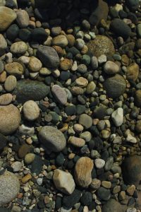 Close-up multi-colored river stones of different sizes covering the ground.