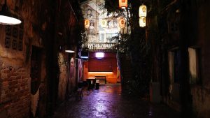 A narrow alleyway featuring a bench illuminated by soft lights, creating a serene and inviting atmosphere. 