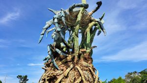 A large, artistic sculpture depicting a fantastical creature with multiple limbs and a vibrant color palette of blue and green.