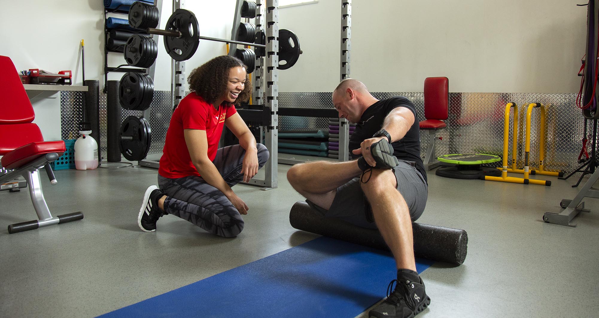 A student employee helps a recreation services user with proper stretch techniques.