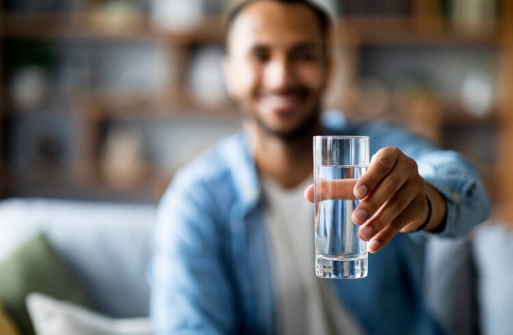 man holds drinking water in outstretched arm