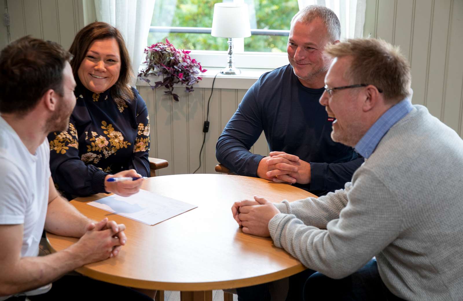 Tre menn og kvinne sitter rundt et bord