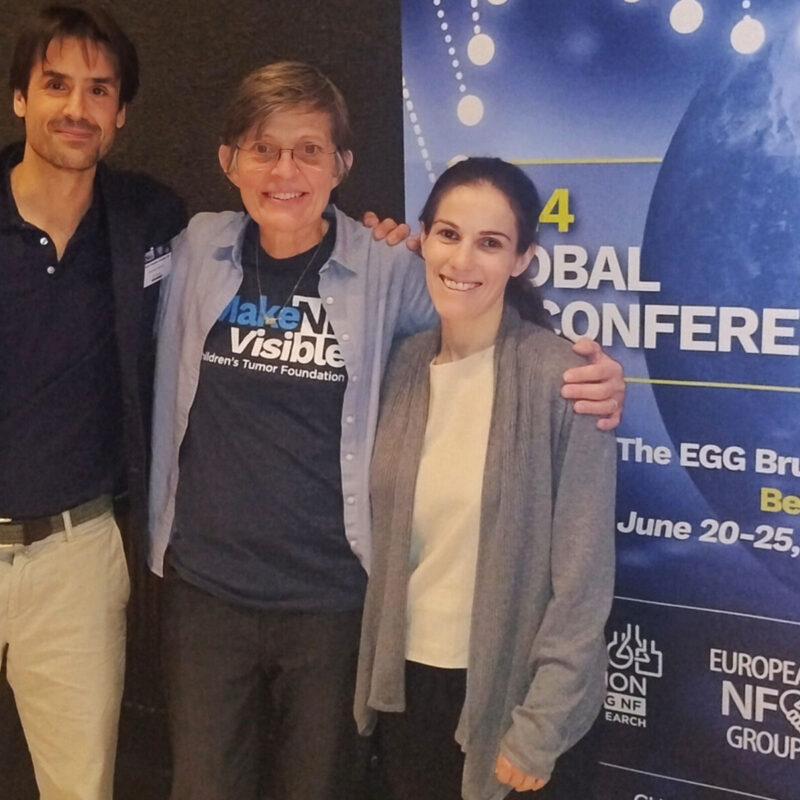 Three people smiling and posing in front of a banner for the 2024 Global Conference, held in Brussels from June 20-25, 2024.