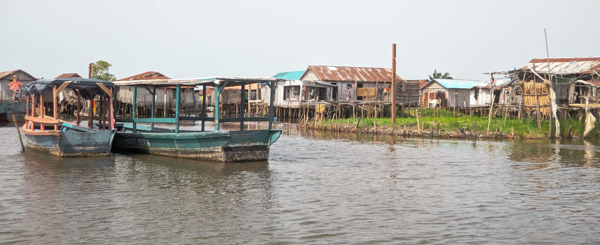 Floating/stilt village in Benin with waterway and boats in front of stilt houses. 