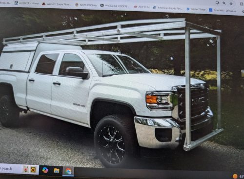 white GMC Sierra 2500HD or 3500HD pickup truck with a custom-built aluminum truck rack