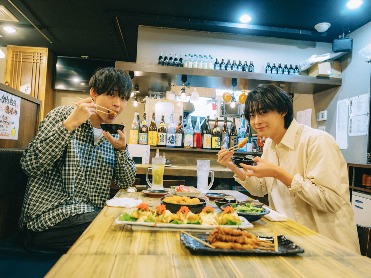 居酒屋で料理をほおばる水沢林太郎と豊田裕大