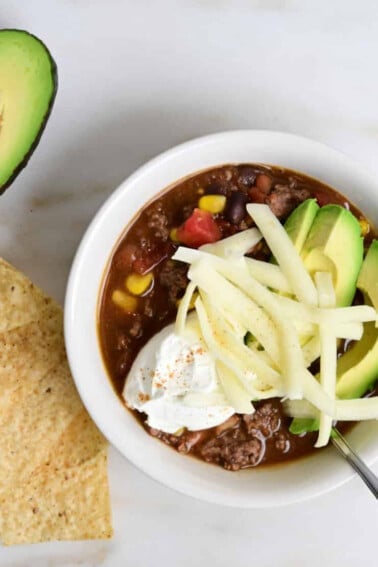 Best easy taco soup topped with avocado, cheese, sour cream, and served with tortilla chips.