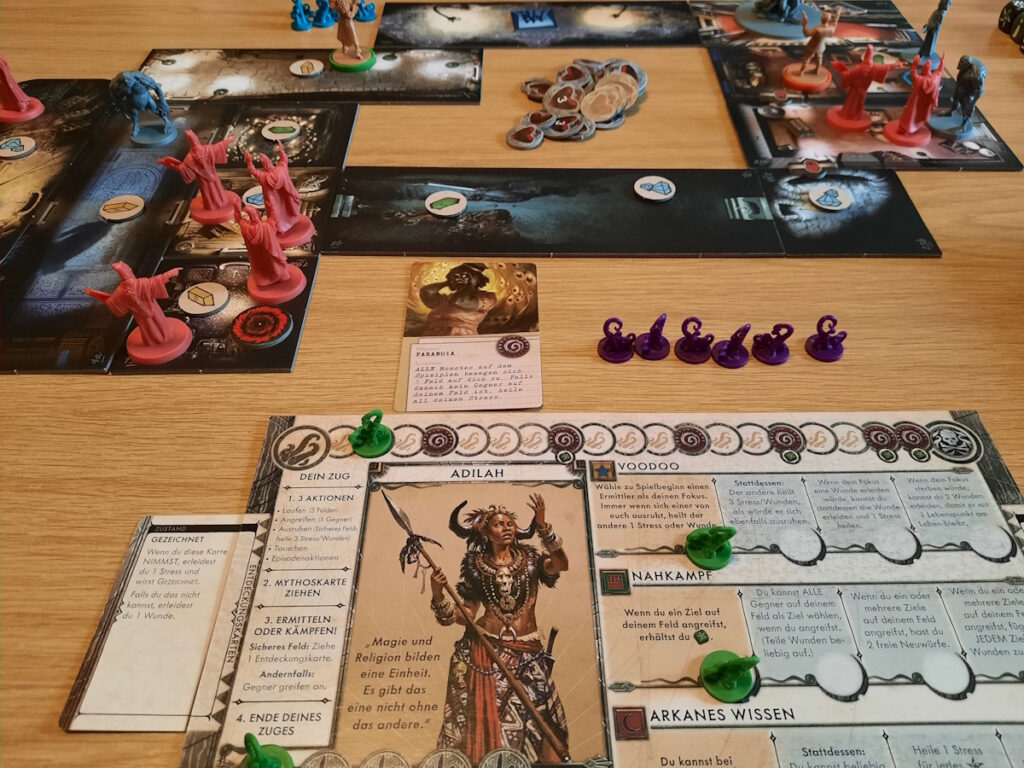 Der Aufbau einer Brettspielrunde von "Death May Die". Im Vordergrund ist mein Charakter - eine Schamanin - zu sehen. Im Hintergrund sind einige Räume mit diversen Monstern und Kultisten zu erkennen.