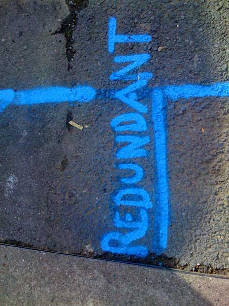 The word redundant spray painted in blue on a wall