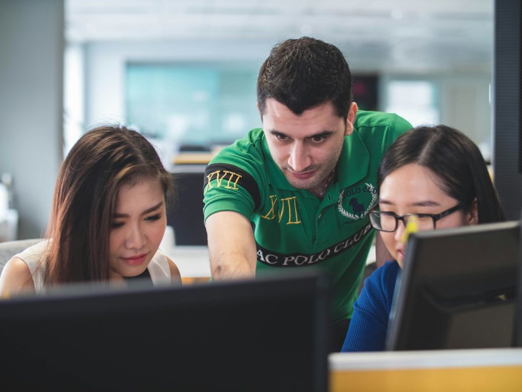 Three people collaborating at a desk on a computer
