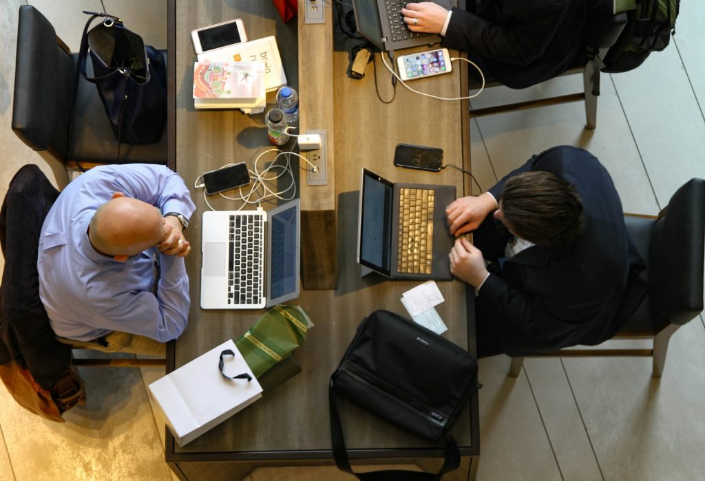 people at a desk on laptops and phones