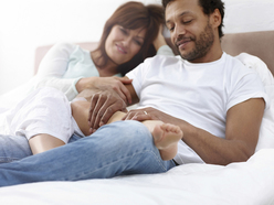 A pregnant woman lounging with her partner