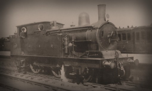No.1080 at Southend after rebuilding with the 160psi boiler with a strengthening plate rivetted to the outside frame behind the front axlebox. The paintwork again has a haze of grime on it, and again the smokebox has been burnt away from being worked hard on the fast outer suburban trains. The loco is showing the headcode for Shenfield and Southend local passenger trains, and the coaching stock behind is a mix of widened and six-a-side suburban 4-wheelers. Photograph © Public Domain.