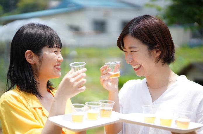 複数のカップの飲み物を飲み合う女性
