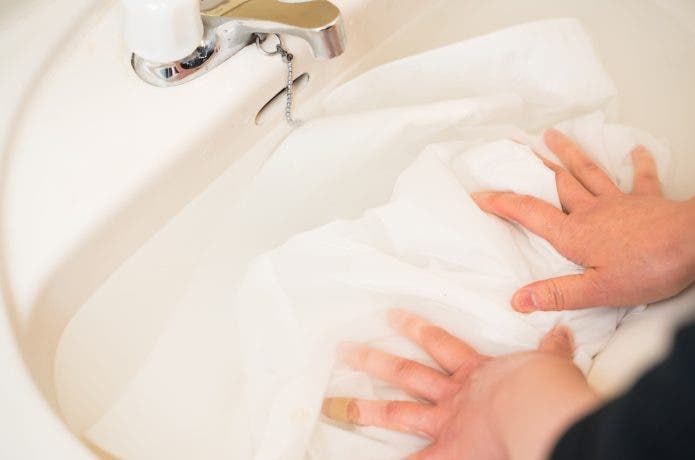 タオルを洗剤液につけている人