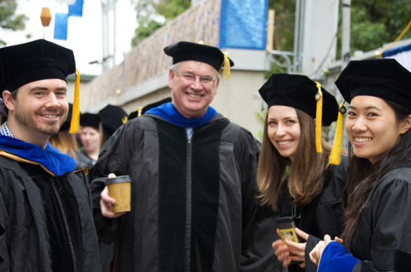 photo of conolly with three graduating students in regalia at commencement