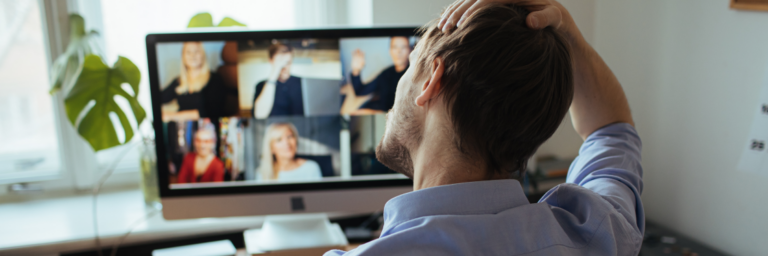 Man in a blue shirt participating in a video conference from his home office.